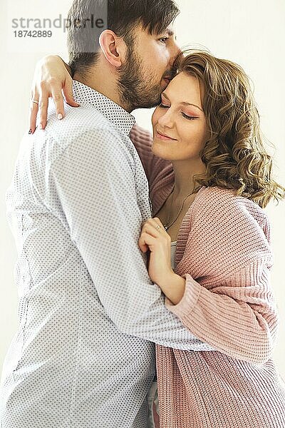 Seitenansicht des Inhalts liebendes Paar sanft umarmt auf weißem Hintergrund zu Hause