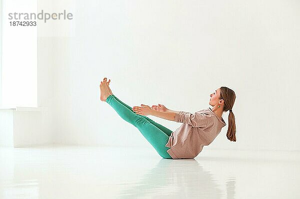 Ruhige Frau in Sportkleidung übt Yoga in Firefly Pose  während sie balanciert und wegschaut