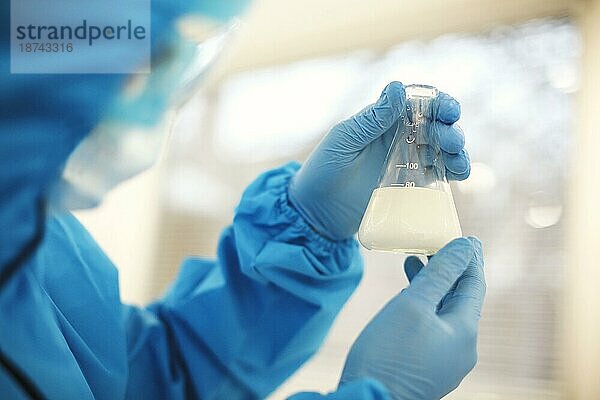 Wissenschaftlerin im Labor  die Proben in einem Reagenzglas untersucht  arbeitet in einem afrikanisch amerikanischen Frauen Genlabor und trägt geschützte Kleidung