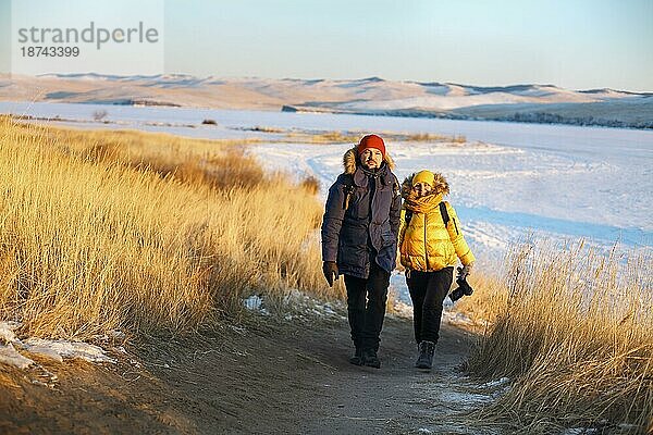 Romantisches Touristenpaar in warmer Wintersportkleidung mit Touristenrucksäcken  die in den verschneiten Bergen bei einem unglaublichen Sonnenuntergang wandern. Ogoi Insel  Baikalsee. Familie  Ruhe
