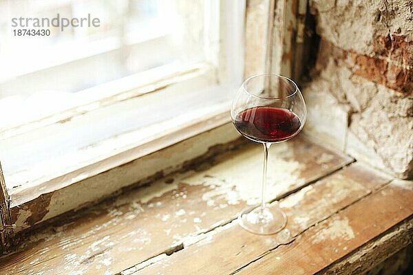 Ein Weinglas mit Rotwein während einer Party mit Kopierraum. Feiern und Urlaub Konzept
