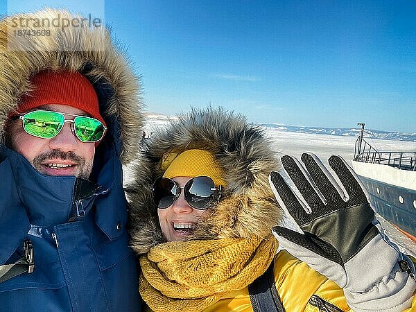 Selbstporträt eines glücklichen Paares auf dem zugefrorenen winterlichen Baikalsee. Transparentes Eis. Reisen im Winter  aktive Erholung  Sport  Urlaub