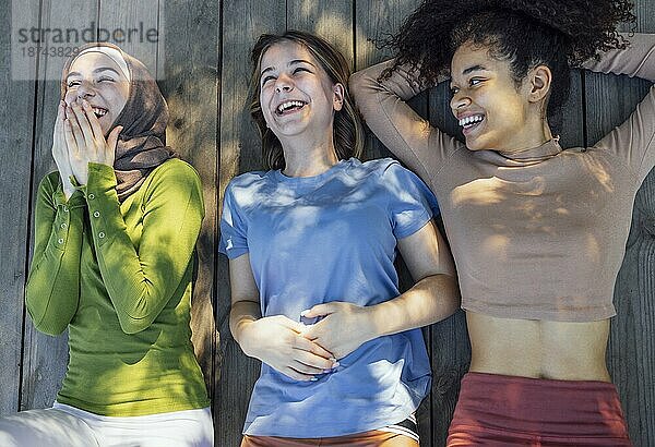 Multirassische junge Teenager Freundinnen ruhen sich nach dem Sporttraining im Park aus  lachen und haben Spaß zusammen. Diversität  Sport und Freundschaft Konzept