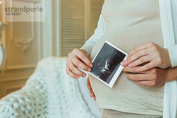 Familienplanung. Cropped Schuss der liebevollen Ehemann umarmt seine schwangere Frau hält Ultraschall Scan in den Händen  Mann und Frau in Erwartung des Wartens auf neue Baby zu Hause. Schwangerschaft Konzept