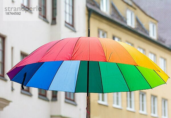Offener regenbogenfarbener Regenschirm in der Stadt