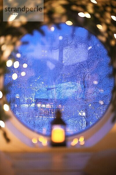 Weihnachtsdekoration zu Hause. Atmosphärische Indoor Foto mit alten Vintage leuchtenden Laterne durch runde Fenster mit Baumzweig und Weihnachtsbeleuchtung dekoriert. Einstellung Urlaub Stimmung während der Winterferien im Haus