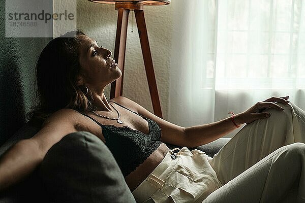 Latina Frau auf dem Sofa zu Hause  die nach einem harten Arbeitstag eine Pause einlegt