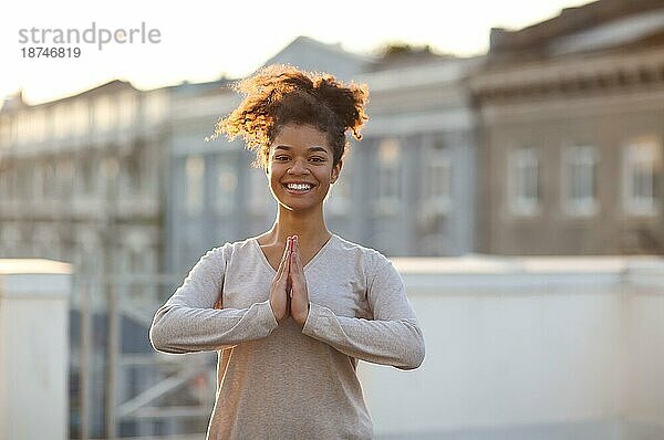 Foto einer Frau  die in Yogapose auf einer Matte steht und Yoga praktiziert  eine Frau  die die Namaste Geste macht  während sie in einem Raum meditiert. Meditation und Achtsamkeit Konzept