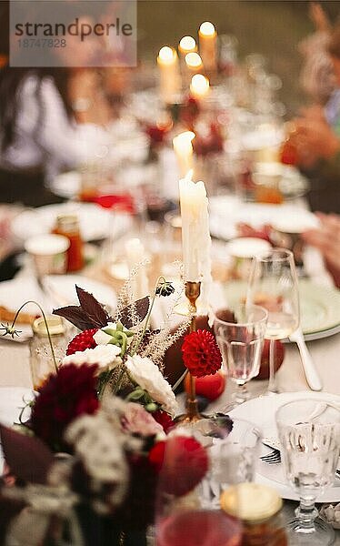 Soft Fokus von frischen Blumen und brennenden Kerzen inmitten von Geschirr auf Bankett Tabelle während der Veranstaltung platziert