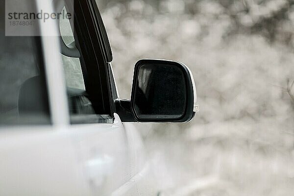 Weichzeichner von weißem Fahrzeug mit Außenspiegel in verschneiter Landschaft im Winter geparkt