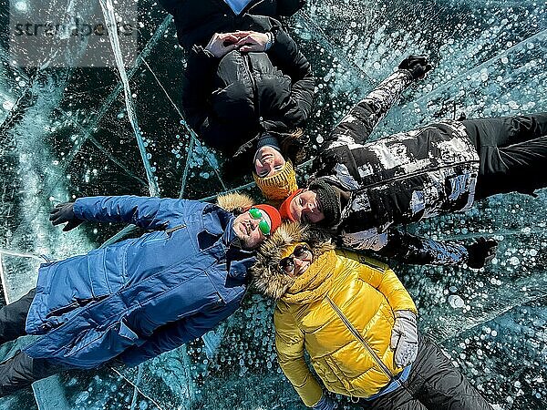 Gruppe von glücklichen Touristen Freunde auf dem Hintergrund der Eis Wintersee Baikal am sonnigen Tag. Winter Baikalsee  Russland. Konzept der Freiheit  Reisen und Glück
