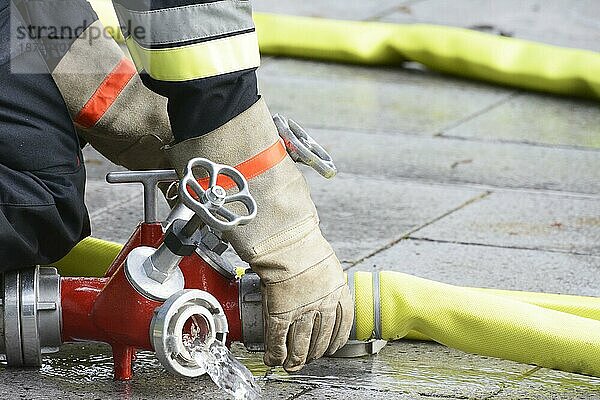 Hand eines Feuerwehrmannes  der einen Feuerlöschschlauch mit einer Anschlussvorrichtung verbindet