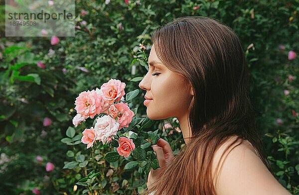 Mode Outdoorfoto von schönen sexy Frau mit dunklen Haaren posiert in Blüte Garten mit Rosen Sträucher