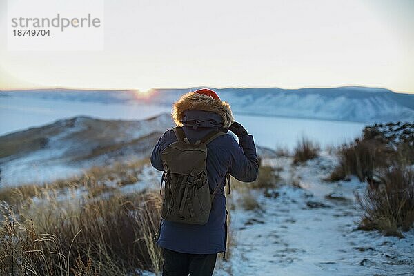 Junger Mann steht im Winter gefrorenen Natur und beobachten ruhigen Winter nebligen Sonnenaufgang. Thinking Konzept  volle Freiheit Foto  schöne Landschaft. Ogoy Insel  Baikalsee  Sibirien  Russland  Europa