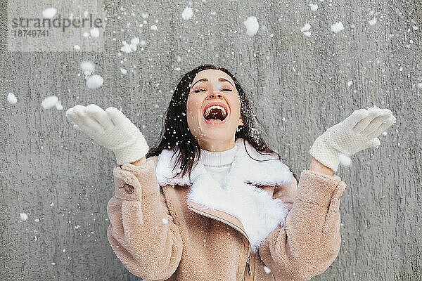Optimistische junge Frau lächelt  während sie an einem sonnigen Wintertag auf der Straße Spaß hat
