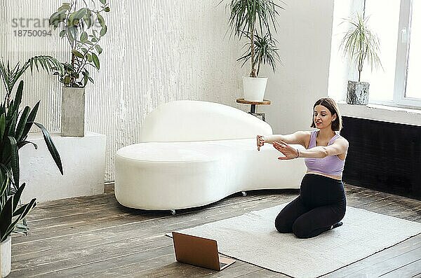 Glückliche brünette schwangere Frau mit Laptopcomputer macht Yoga zu Hause. Sport  Fitness und Menschen Konzept