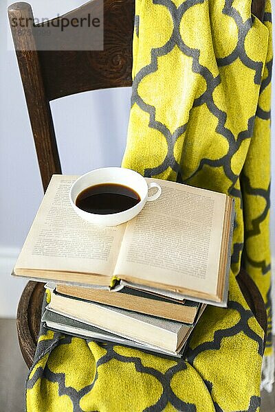 Tasse Kaffee und Buch auf dem Holzstuhl