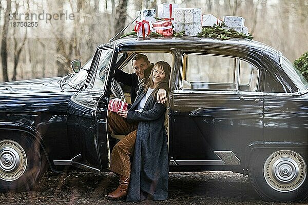 Liebender Mann und Frau im Retro Autofenster mit Weihnachtsgeschenken auf dem Dach im Park