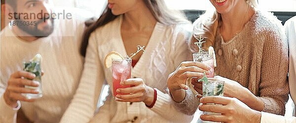 Junge Männer und Frauen trinken Cocktails auf einer Party. Feiern und Party Konzept