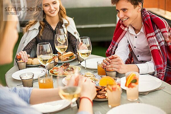 Fröhlicher Mann und lächelnde Frauen  die während eines Banketts am Tisch sitzen