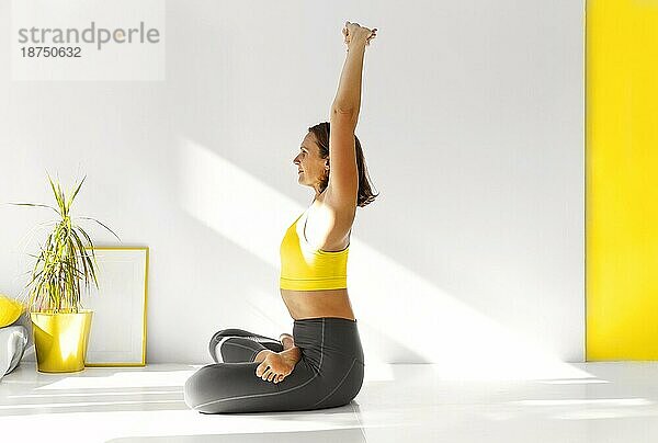 Seitenansicht einer ruhigen Frau in Sportkleidung  die Yoga in der Firefly Pose praktiziert  während sie auf den Armen balanciert und wegschaut
