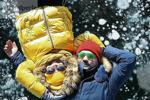 Glückliches Paar  das auf dem gefrorenen Baikalsee im Winter liegt. Transparentes febrarisches Eis mit Blasen. Reisen im Winter  aktive Erholung  Sport  Urlaub