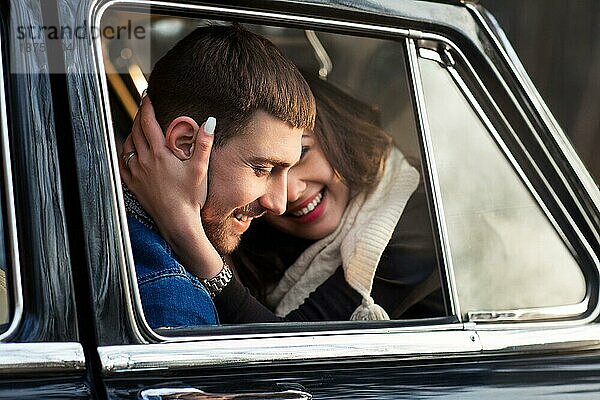 Liebender Mann und Frau umarmen sich im Retroauto im Park
