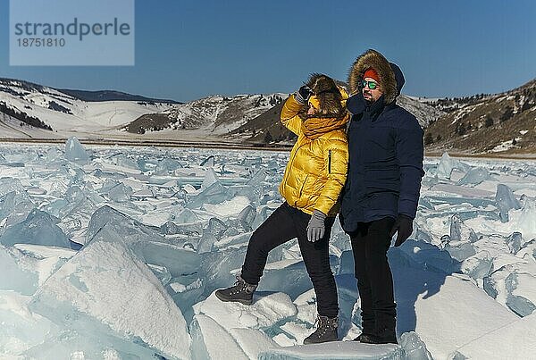 Glückliches Paar auf dem zugefrorenen Winter Baikalsee. Transparentes Eis. Reisen im Winter  aktive Erholung  Sport  Urlaub