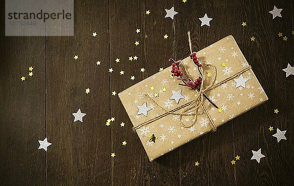 Draufsicht auf eine stilvolle  mit Beeren und Sternen geschmückte Geschenkbox  die während der Weihnachtsfeier auf einem Holztisch steht