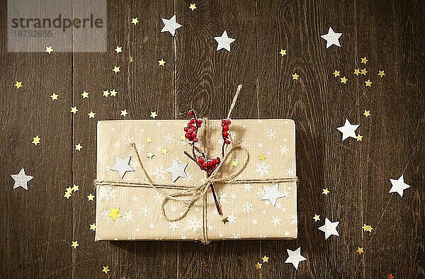 Draufsicht auf eine stilvolle  mit Beeren und Sternen geschmückte Geschenkbox  die während der Weihnachtsfeier auf einem Holztisch steht