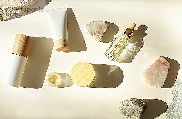 Draufsicht auf Flaschen mit verschiedenen kosmetischen Produkten inmitten von Steinen auf weißem Hintergrund