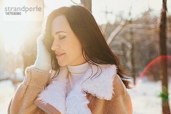 Optimistische junge Frau lächelt  während sie an einem sonnigen Wintertag auf der Straße Spaß hat