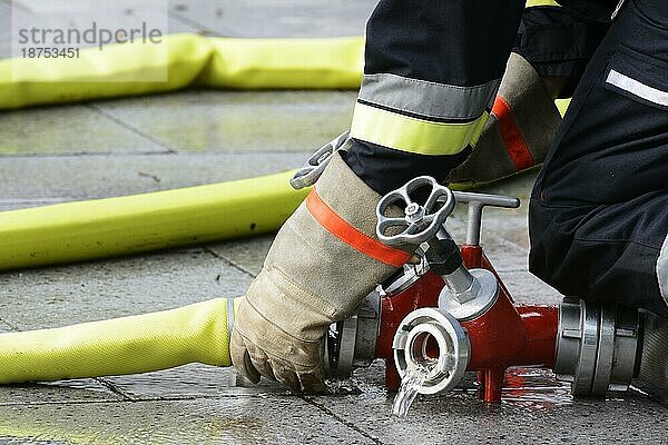 Hand eines Feuerwehrmannes  der einen Feuerlöschschlauch mit einer Anschlussvorrichtung verbindet