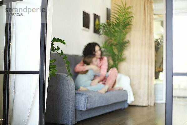 Gemütliche inländische Foto von glücklichen Mutter und Tochter im Schlafanzug auf dem Sofa am Morgen entspannen  junge schöne Mutter und kleines Mädchen Kind verbringen faul Familie Wochenende zu Hause. Familie und Mutterschaft Konzept