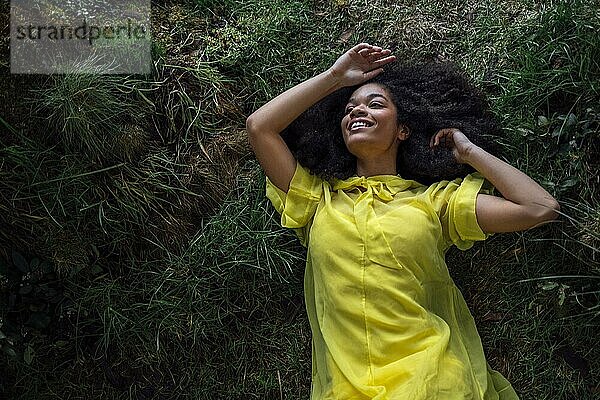 Mode und Schönheit Schießen eine charmante Mixed Race Mädchen in einem langen gelben Kleid. Schönes Mädchen auf dem Gras in ihrem gelben Kleid in ungewöhnlichen Studio. Junge Frau genießt die Natur