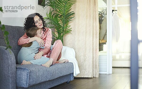 Gemütliche inländische Foto von glücklichen Mutter und Tochter im Schlafanzug auf dem Sofa am Morgen entspannen  junge schöne Mutter und kleines Mädchen Kind verbringen faul Familie Wochenende zu Hause. Familie und Mutterschaft Konzept