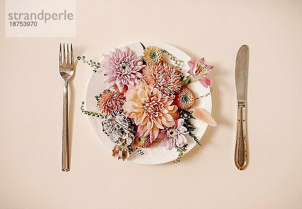 Draufsicht auf Gabel und Messer Schneiden und Teller mit natürlichen Blumen auf dem Teller gegen Pfirsich Hintergrund