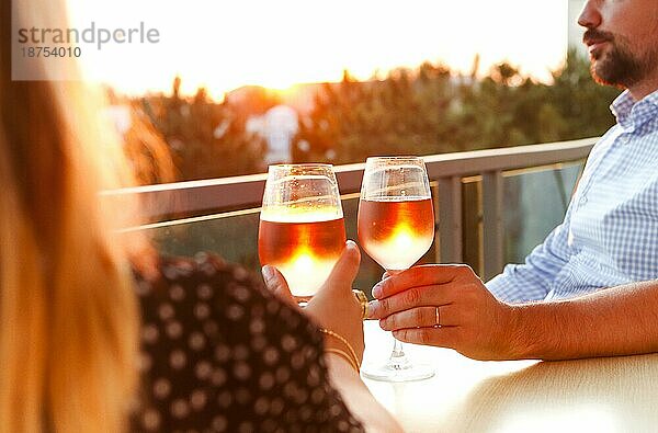 Pärchen beim Mittagessen auf der Terrasse mit Rosenwein bei Sonnenuntergang