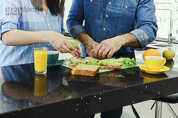 Mann im Gespräch mit seiner Frau Kochen gesundes Essen genießen Vorbereitung romantisches Abendessen in der Küche. Paar bereitet Abendessen vor. Gesundes Essen  Diät. Gemeinsam kochen in der modernen Küche