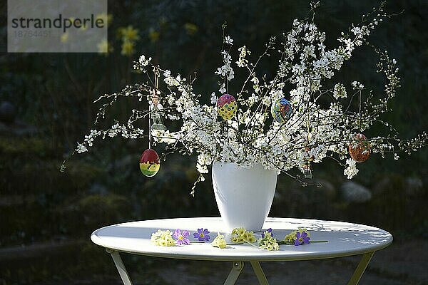 Osterstrauß mit handbemalten Ostereiern in einer Vase im Garten