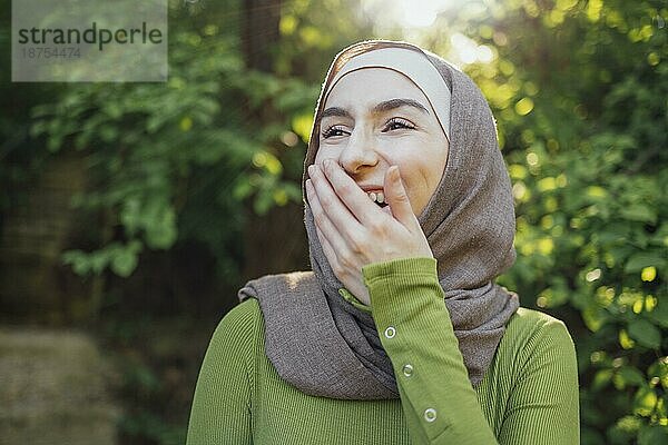 Schöne freudige Teenager High School Mädchen trägt bunte muslimische Kleidung mit Spaß im Freien