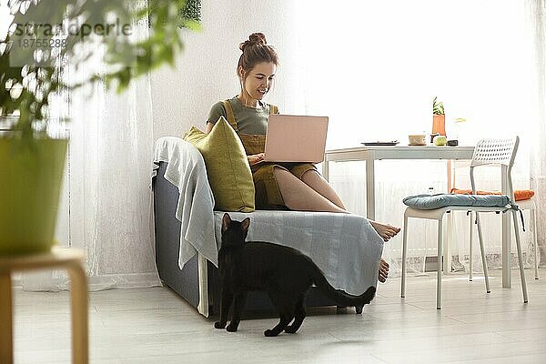 Junge barfuß Frau sitzt auf dem Sofa in der Nähe von Tisch und Surfen Netbook am Morgen zu Hause