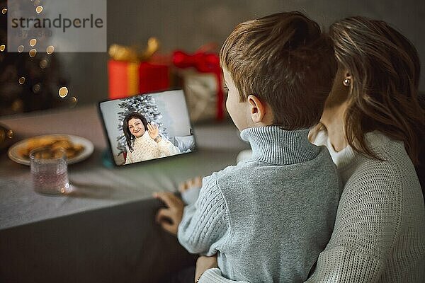Glückliche junge Frau mit kleinem Sohn  im Gespräch mit Freunden auf virtuellem Zoom Videogespräch  feiern Neujahrsparty in Urlaub Remote Online Konferenz Chat auf Computer zu Hause
