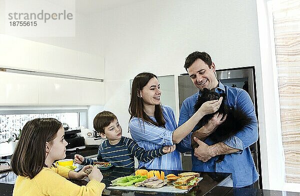 Happy Fröhlich Familie genießen gesundes Frühstück zusammen in der Küche zu Hause Wochenende mit kleinen lustigen Hund