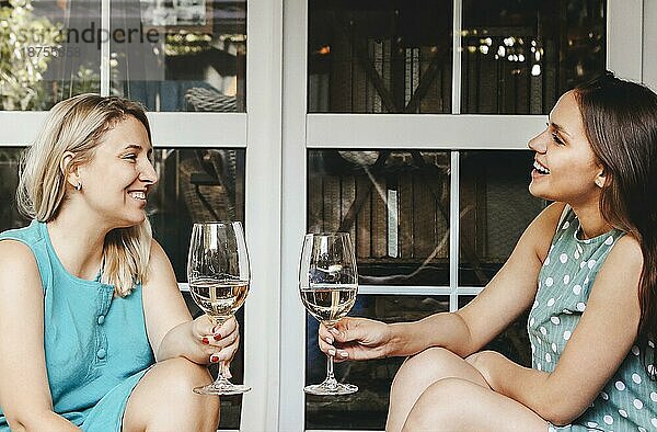 Zwei stilvolle glückliche Frauen versammeln sich im Sommer für eine Party und genießen Zeit zusammen trinken Weißwein