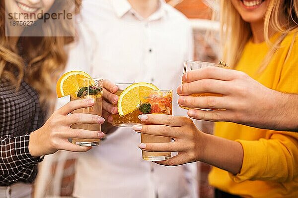 Anonyme Männer und Frauen stoßen mit Gläsern von Fruchtcocktails an und bringen auf einer Party einen Toast aus