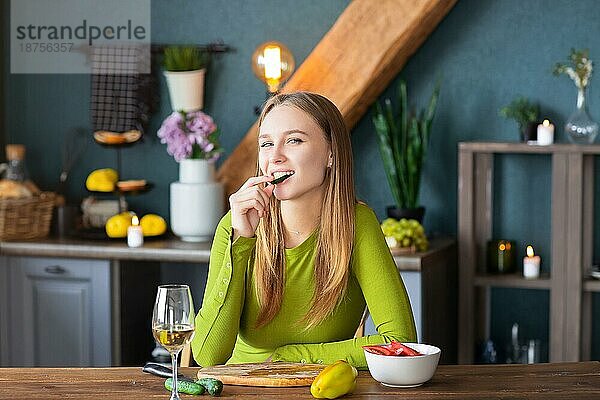 Happy blonde Frau macht Salat Küche Gemüse kochen und trinken Weißwein in der Küche. Gesundes Kochen Konzept