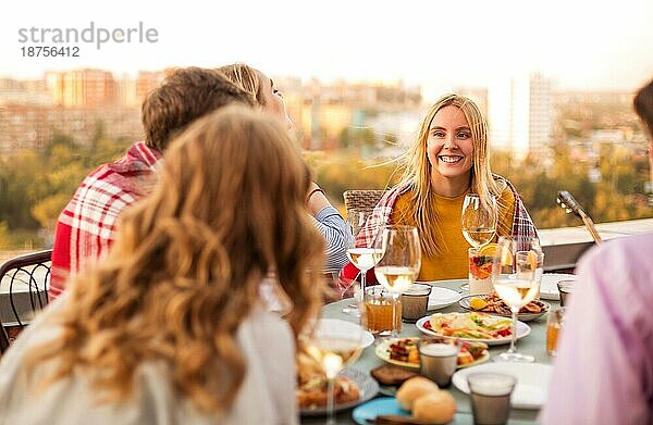 Fröhlicher Mann und lächelnde Frauen  die während eines Banketts am Tisch sitzen