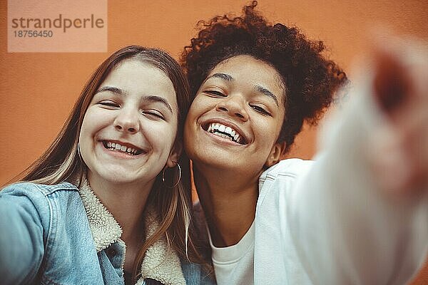 Selbstporträt von zwei glücklichen  fröhlichen Teenagermädchen verschiedener Rassen  die in die Kamera lächeln und die Freundschaft genießen  multiethnische beste Freundinnen  die ein Selfiefoto machen und Spaß haben  während sie Zeit miteinander verbringen