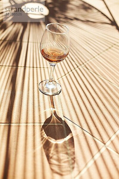 Hohe Winkel von Glas Wein auf Backstein Barriere auf sonnigen Sommertag im Hof platziert